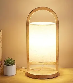 Portable bedside table lamp with a built-in handle, featuring three adjustable color temperatures. Designed with a natural wood base and a linen fabric shade, this modern LED lamp is ideal for bedrooms, living rooms, offices, and dorm rooms. LED bulb included.